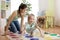 Young mother playing twister with her daughters. Cheerful family indoors. Happy family playing together in living room.