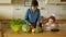 A young mother is preparing dinner in the kitchen. She cuts the carrots. A little daughter helps my mother. The girls