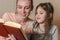 Young mother reads a book to her daughter, happy family