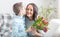 Young mother receiving a bouquet full of tulips and a ovely kiss from his son during national mothers day