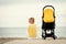 Young mother relaxing on beach with baby stroller