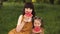 Young mother resting with her daughter in park touch the noses and holding a watermelon