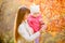 Young mother shows kid girl fallen leaves on tree