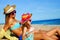 Young mother sitting with daughter on beach.