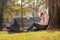 Young mother sitting in a park and reading a story to her baby