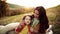 A young mother with a small daughter in autumn nature at sunset, eating biscuits.