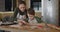 Young mother and son cooking cookies together in the kitchen. Mom and baby boy cut out homemade cookies with shapes form