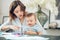 Young mother soothing crying baby sitting at table