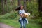 young mother is spinning with a baby in her arms. happy mom dancing with toddler on the background of nature and forest