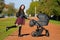 Young mother with a stroller. family, child and parenthood concept - happy mother walks with a stroller in the park