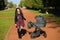 Young mother with a stroller. family, child and parenthood concept - happy mother walks with a stroller in the park