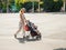 Young mother with a stroller in the foreground. In the background is a group of cyclists