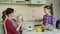 Young mother talking photo on smartphone camera of her cute smiling daughter cooking cutting vegetables in the kitchen