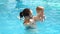 A young mother teaches her son to dive into the water in the pool, slow motion.