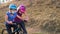 A young mother teaches his daughter to ride a Bicycle in medical masks and a Bicycle helmet in nature near the hill. Protection