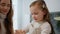 Young mother teaching daughter cooking indoor portrait. Focused kid making dough