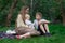 Young mother with two children sitting on picnic blanket in the Park. Older and younger siblings