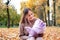 Young mother on a walk with a baby in the autumn park. Mom smiles and looks at the child with tenderness