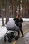 young mother on a walk with her baby. girl with a baby in a stroller in the winter on a walk.