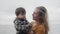 A young mother walks with her son on the shores of the picturesque Lake Ontario