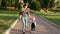 Young mother walks holding daughter`s hand in a public park