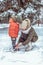 A young mother, a woman fastens ski rack for a boy of 2-3 years old son. In winter in the park outside. Caring for the