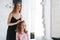 Young mother woman with long hair in black dress and little tween girl daughter in pajamas having fun in the morning at home,