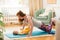 Young mother working out at home on a mat with baby. Interior of a nursery room. Woman practicing yoga together with child