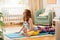 Young mother working out at home on a mat with baby. Interior of a nursery room. Woman practicing yoga together with child