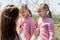 Young mother zips up pink sweaters for her twin daughters in an Apple orchard