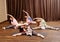 Young mothers and their babies doing yoga exercises on rugs at fitness studio.