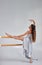 Young motivated woman in skirt stretching legs on ballet barre in studio