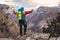 Young mountaineer standing with backpack on top of a mountain