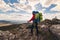 Young mountaineer standing with backpack on top of a mountain