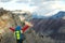 Young mountaineer standing with backpack on top of a mountain