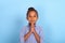 Young mulatta frizzy girl  prays against a blue background with copy space