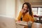 Young multi-cultural female blowing her nose while on a business call. Sick and working from home on laptop