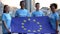 Young multi-racial volunteers holding European Union flag, international unity