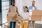 young multiethnic coworkers holding cardboard boxes and smiling at camera