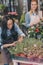 Young multiethnic florists in aprons working with flowers in flower shop