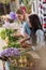 Young multiethnic florists arranging beautiful fresh flowers in flower shop