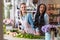 Young multiethnic florists arranging beautiful fresh flowers in flower shop