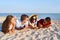 Young multiethnic group of millenials relaxing on the beach towel near sea on white sand. Stylish friends hanging on