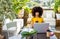 Young multiethnic woman working at start up project sitting on table in coworking space holding smartphone discussing work.