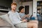 Young multinational couple using laptop and reading book at home