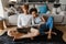 Young multinational couple using laptop and reading book at home