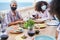 Young multiracial group of friends having dinner and wearing protective masks - Focus on african girl