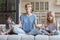 Young mum and little daughter meditate on home couch