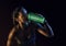 Young muscular build woman silhouette drinking water of bottle.