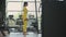 Young muscular hispanic woman doing Lunges exercise with dumbbells in the gym In yellow sportswear. Female athlete